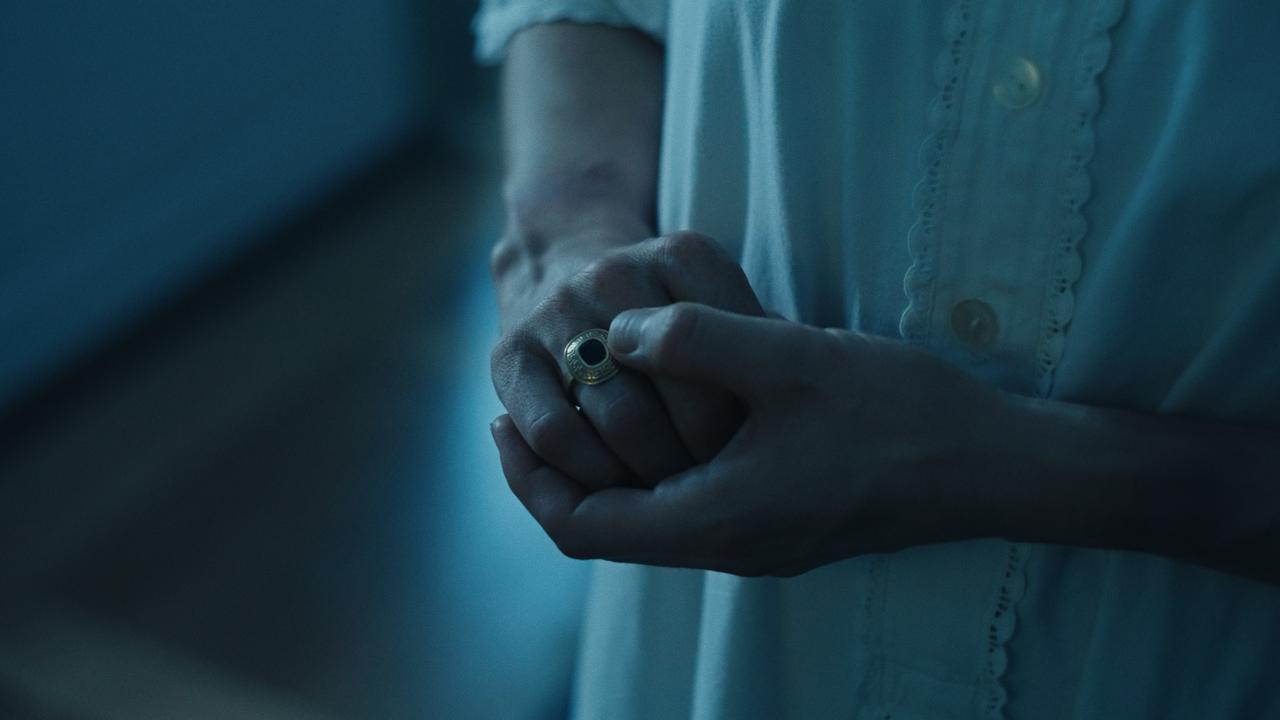 Standbild aus Evelyne: Hände in blauem Licht, an einem Finger ein goldener Ring