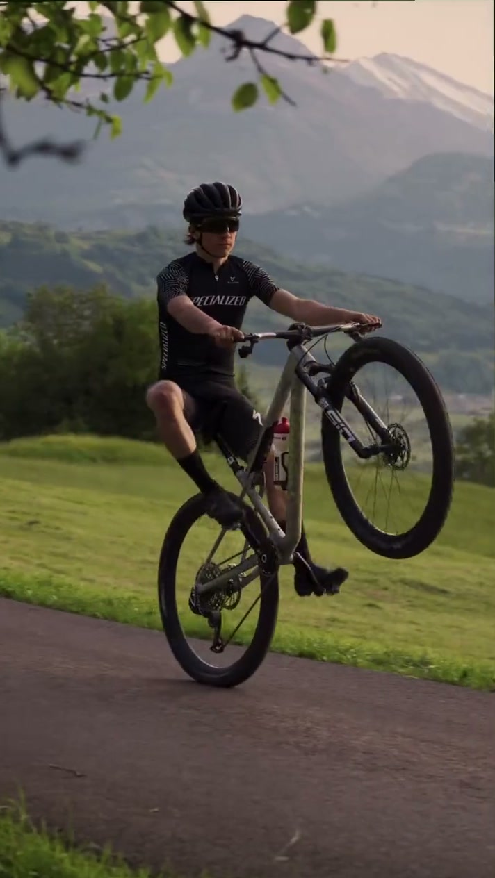 Gian Sidler fährt einen Wheelie auf dem Mountainbike, im Hintergrund Berge